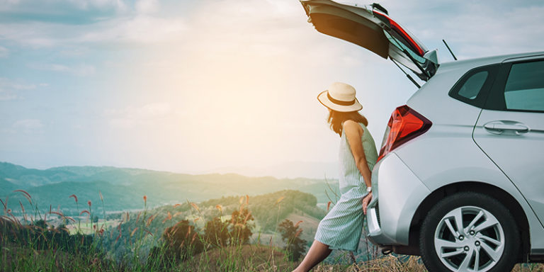 women leaning on car